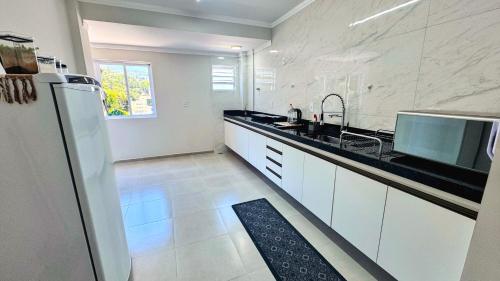 a white kitchen with a sink and a refrigerator at Morada Belli - Apartamento no Centro in Serra Negra