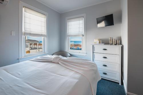 a white bedroom with a bed and two windows at Grand Victorian an ICONA Boutique Collection in Spring Lake