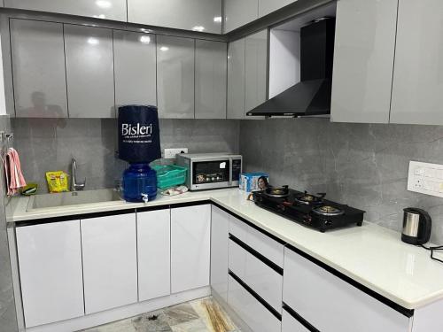 a kitchen with white cabinets and a microwave at Cozy nest 2bhk by LWB in New Delhi