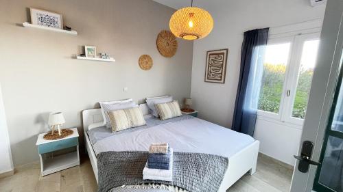 a white bedroom with a bed and a window at Kalimera Kalyves Apartment in Kalyves