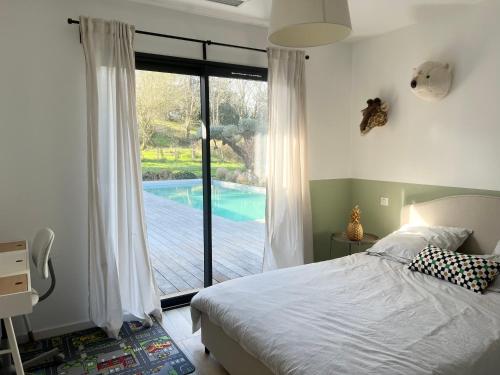 une chambre avec un lit et une vue sur une piscine dans l'établissement Villa avec piscine, proche Bayonne, à Lahonce