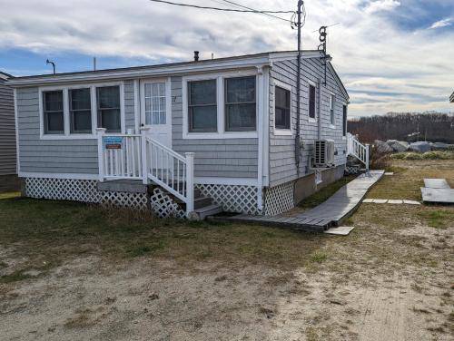 a white house with a porch on a field at Beach Cottage in Saco