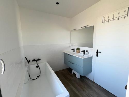 une salle de bain avec un lavabo, une baignoire et un miroir dans l'établissement Villa avec piscine, proche Bayonne, à Lahonce