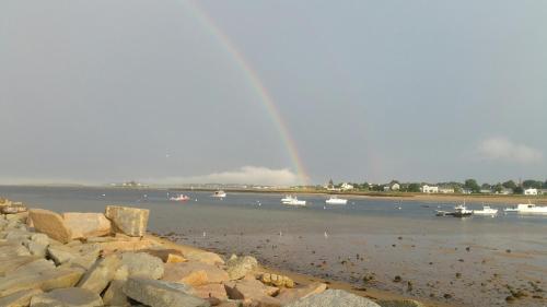 a group of boats in the water with a rainbow at Beach Cottage in Saco
