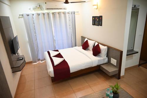a bedroom with a bed with red pillows at Hotel Sun Bright Residency Manipal in Manipala