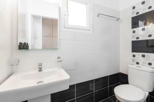 a white bathroom with a sink and a toilet at Villa Libertad in Imerovigli