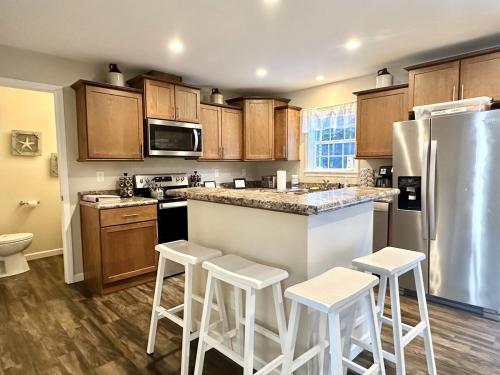 eine Küche mit Holzschränken, einem Kühlschrank und Stühlen in der Unterkunft Waterfront Family & Pet Friendly Home with Hot Tub "Sandpiper Shores" in Gouldsboro