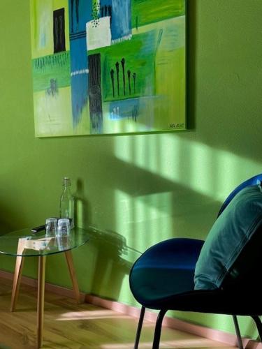 a green room with a glass table and a blue chair at CURUNA Pensiun-Frühstückspension in Scuol