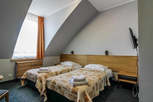 a bedroom with two beds and a tv and a window at Hotel Galion in Gdańsk