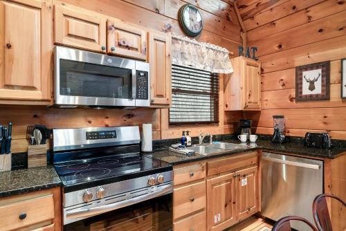 a kitchen with a stove and a microwave at Bearadise-Private Cabin that Sleeps 8, with 3 Full Bathrooms, Pool Table, Board Games and Wet Bar in Sevierville
