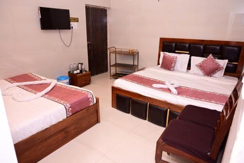 a bedroom with two beds and a tv on the wall at Shri Ram Lalla International in Ayodhya