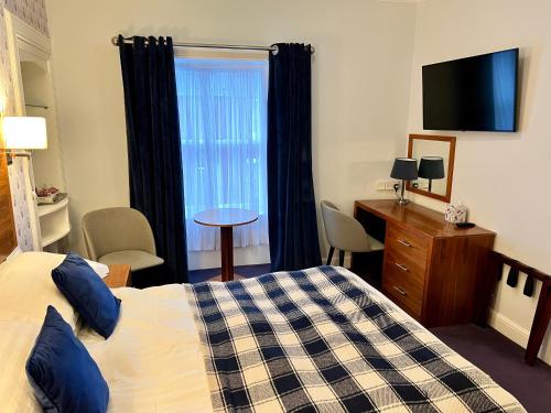 a bedroom with a bed and a window with a television at Selkirk Arms Hotel in Kirkcudbright