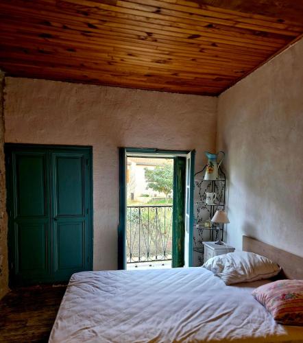 - une chambre avec un lit doté d'une porte verte et d'une fenêtre dans l'établissement La Catalane, à Codalet
