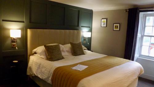 a bedroom with a large bed with a yellow blanket at Selkirk Arms Hotel in Kirkcudbright