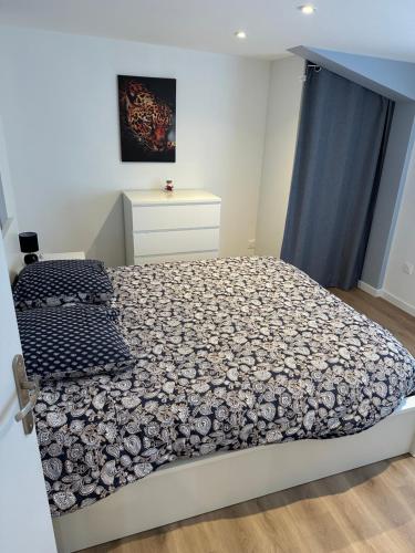 a bedroom with a bed with a black and white comforter at Fully-equipped new apartment in Saint-Germain-Lembron