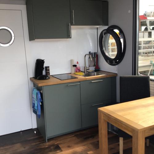 a small kitchen with a sink and a table at exclusives Hausboot "Tante Trost" in Heiligenhafen