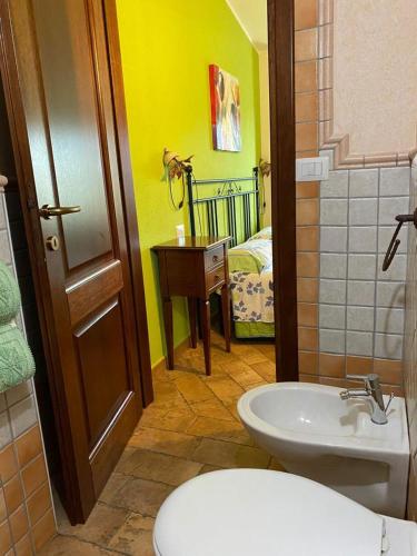 a bathroom with a toilet and a sink with a bed at B&b Su Acu in Dorgali
