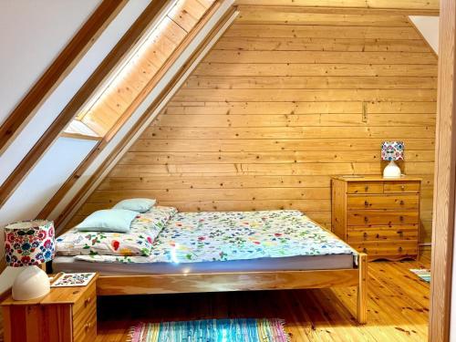 a bed in a room with a wooden wall at Letnia Chata u Romana in Zalewo