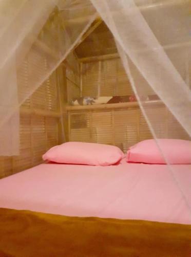a bed with two pink pillows in a room at Bamboo Village in Ban Tai