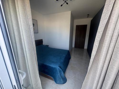Schlafzimmer mit blauem Bett und Vorhängen in der Unterkunft Elegant room with private terrace and bathroom in Gżira