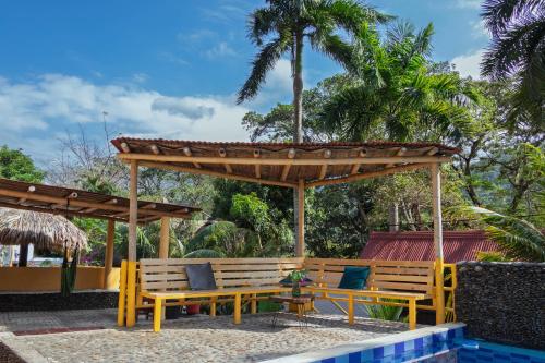 two wooden benches sitting under a wooden pergola at Hotel Manakin Tayrona in El Zaino
