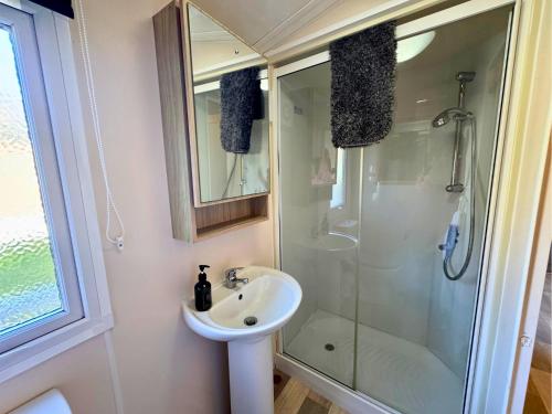 a bathroom with a sink and a shower at Lovely Hot Tub Caravan in Northumberland, Free Golf Access, Dog Friendly in Swarland