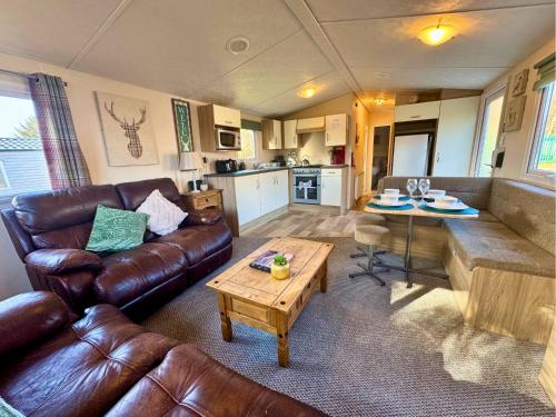 a living room with a couch and a table at Lovely Hot Tub Caravan in Northumberland, Free Golf Access, Dog Friendly in Swarland