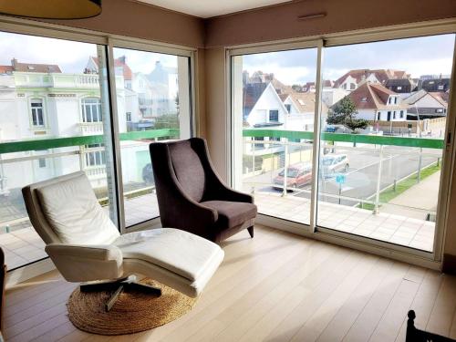 - un salon avec deux chaises et de grandes fenêtres dans l'établissement Appartement 2 chambres avec balcon, à 100m de la plage - FR-1-675-14, à Wimereux