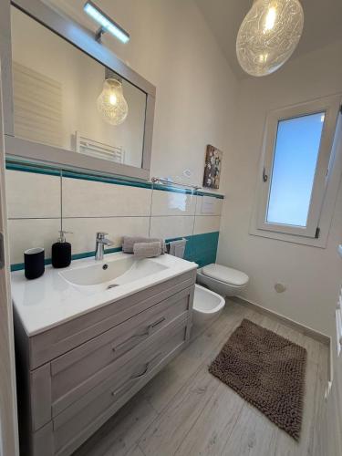 a bathroom with a sink and a toilet and a mirror at Virgilio's House in Tertenìa