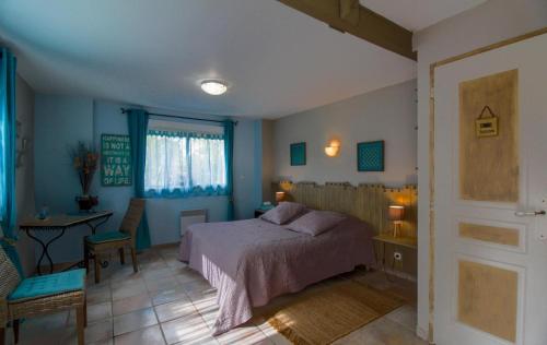 a bedroom with a bed and a table and a window at Le Logis du Canal in Marennes