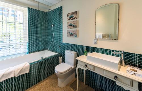 a bathroom with a toilet and a tub and a sink at Cape Heritage Hotel in Cape Town