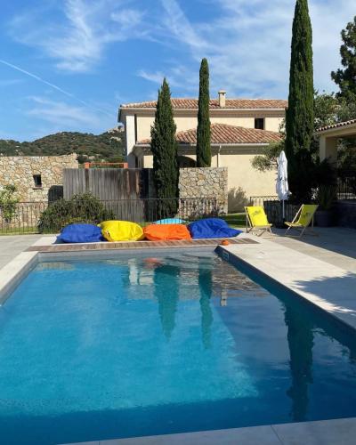 a swimming pool with colorful umbrellas in front of a house at Clos des Oliviers in Lumio