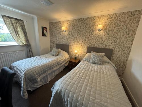 a hotel room with two beds and a window at The Old Stone Trough Country Hotel in Kelbrook