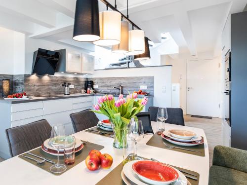 a kitchen and dining room with a table with flowers at FeWo Prora - Sternenblick Penthouse in Binz
