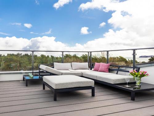 a patio with a couch and tables on a balcony at FeWo Prora - Sternenblick Penthouse in Binz