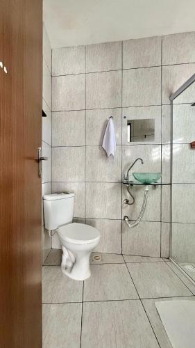 a bathroom with a toilet and a glass shower at Suíte House Pipa in Pipa
