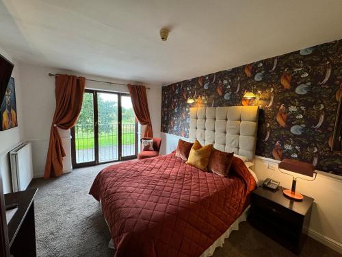 a bedroom with a bed with a red comforter at The Old Stone Trough Country Hotel in Kelbrook