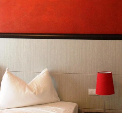 a red lamp next to a bed with a red pillow at La Casa Degli Angeli - Agli Angeli Ristorante Pizzeria in Pertegada