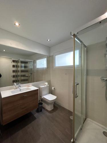a bathroom with a toilet and a sink and a shower at Vila Mar in Porto Covo