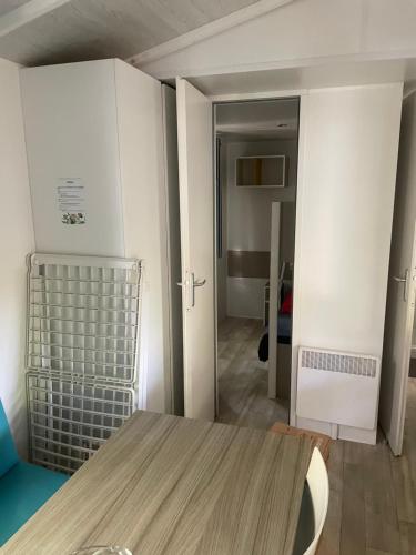 une chambre avec une table et une chambre avec un couloir dans l'établissement Camping Rivages des Landes Mobil-home climatisé et Tv, à Aureilhan