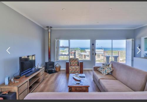 a living room with a couch and a tv at OceansCrest Seaview Apartment in Bettyʼs Bay