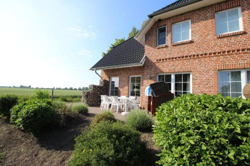a brick house with white chairs and a patio at Bauernhof Höper-Rauert - Nr 10 Wellnesshaushälfte in Neujellingsdorf