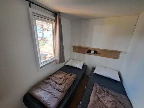 une petite chambre avec deux lits et une fenêtre dans l'établissement Houlgate Mobilhome,3ch, 6pl, camp 5 étoiles, piscines, club enfants, à Houlgate