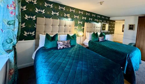 a hotel room with two beds with blue comforters at The Old Stone Trough Country Hotel in Kelbrook