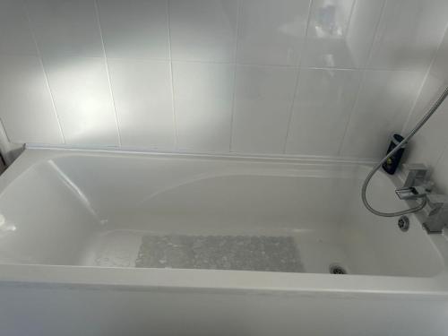 a white bath tub in a white tiled bathroom at A Place to stay in Kettering in Kettering
