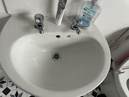 a white bathroom sink with two bottles of toothpaste at A Place to stay in Kettering in Kettering