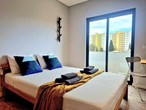 a bedroom with two beds and a large window at Campus 121 - Rooms in Faro