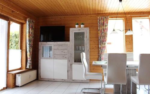 un salon avec une télévision, une table et des chaises dans l'établissement Ferienhaus Nr 32, Typ A, Ferienanlage Blauvogel, Hasselfelde, Harz, à Hasselfelde