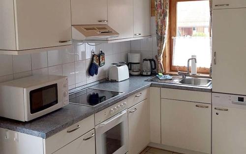 - une cuisine blanche avec un four micro-ondes et un évier dans l'établissement Ferienhaus Nr 32, Typ A, Ferienanlage Blauvogel, Hasselfelde, Harz, à Hasselfelde