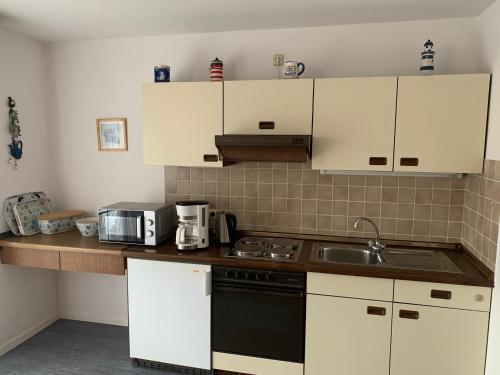 a kitchen with white cabinets and a black stove top oven at FeWo Seeschloss Nr 5 in Dahme